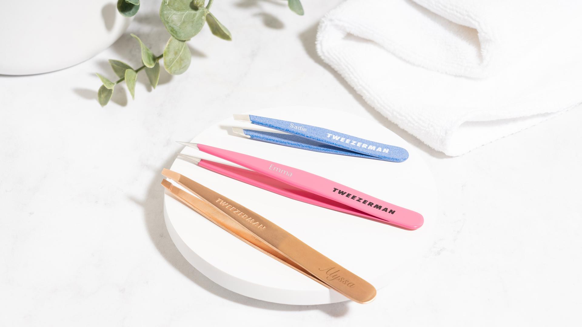 pictured from left to right: ultra precision slant tweezer, pretty in pink point tweezer, and granite sky mini slant tweezer. all items are engraved with differing fonts and names