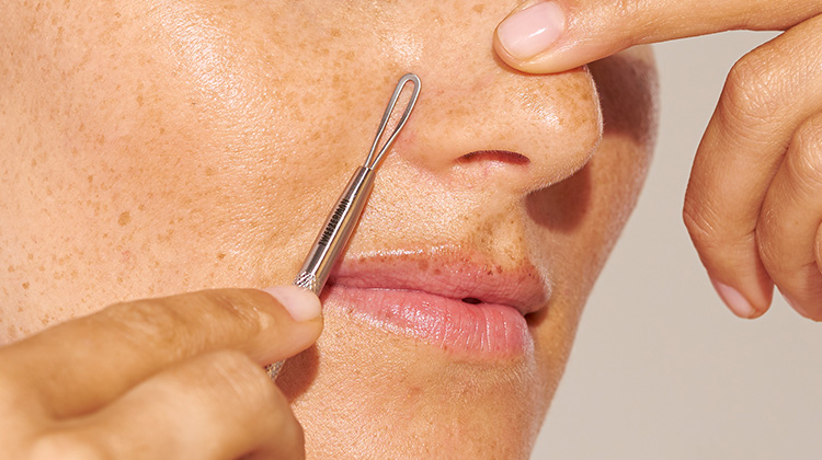 model using skincare tool holding tool up to nose