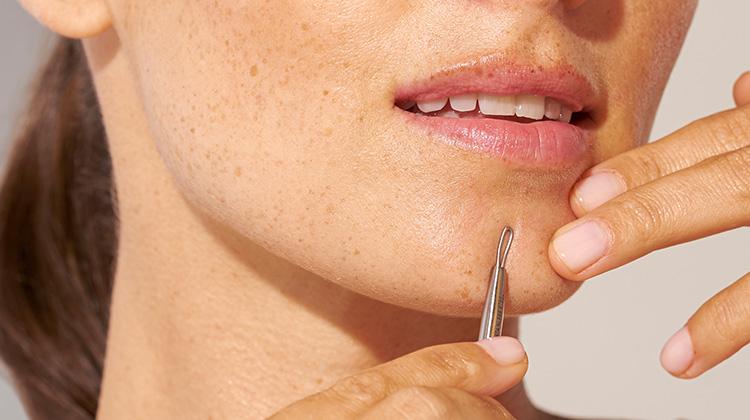 model holding skincare tool up to chin